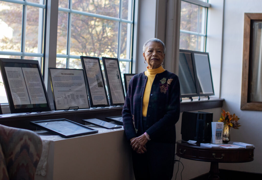 Pollard standing among exhibits in the museum near a window, looking at the camera.