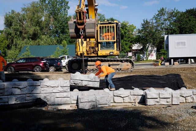 A worker positions a Redi-Rock block, which weighs between two and four tons depending on its size.