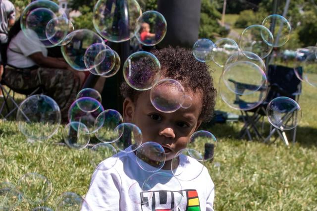 A young attendee is mesmerized by a bubble machine.
