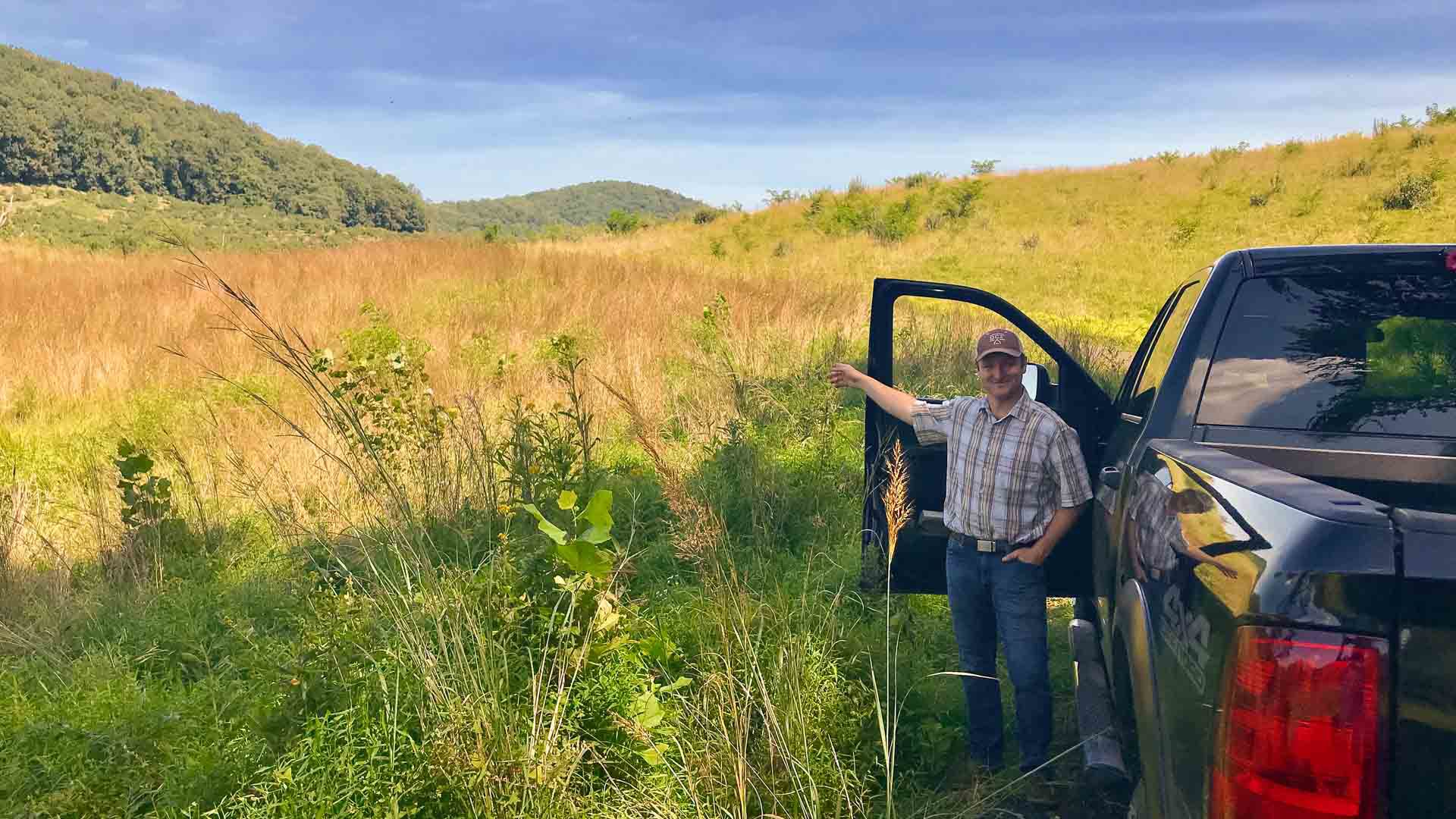 Eldon Farm Manager John Genho stops his pickup truck to point out a field of warm season grasses, surrounded by more weed-infested fescue.