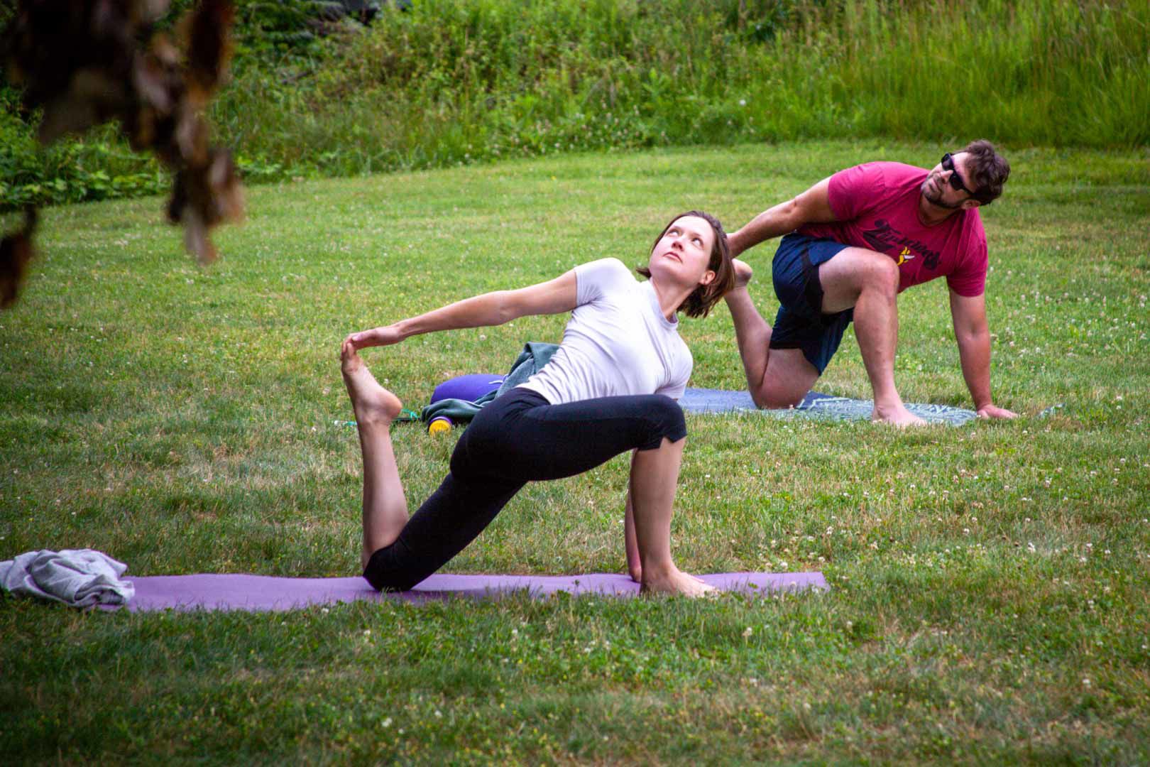 Caitlin Batchelor and Andrew Evans demonstrate the lizard pose during a Stonewall Abbey Wellness outdoor class in Sperryville.