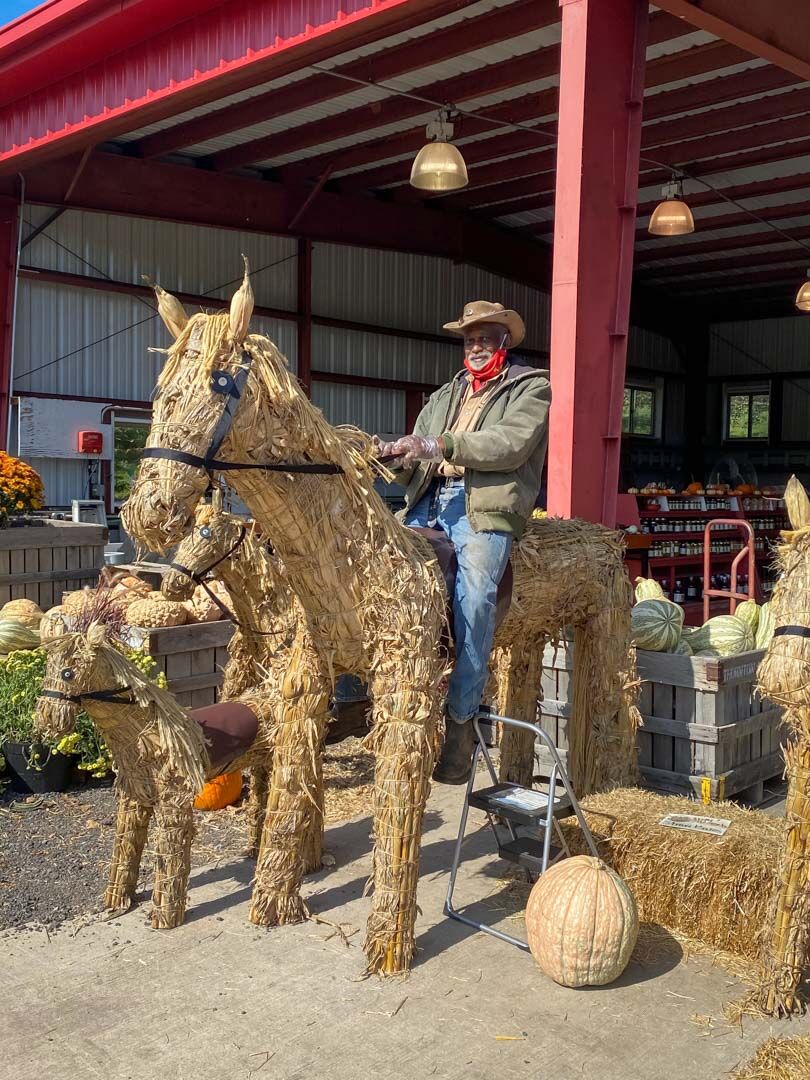 Tommy Starts atop a straw horse at the front of the Thornton River Orchard store in Sperryville, Va.
