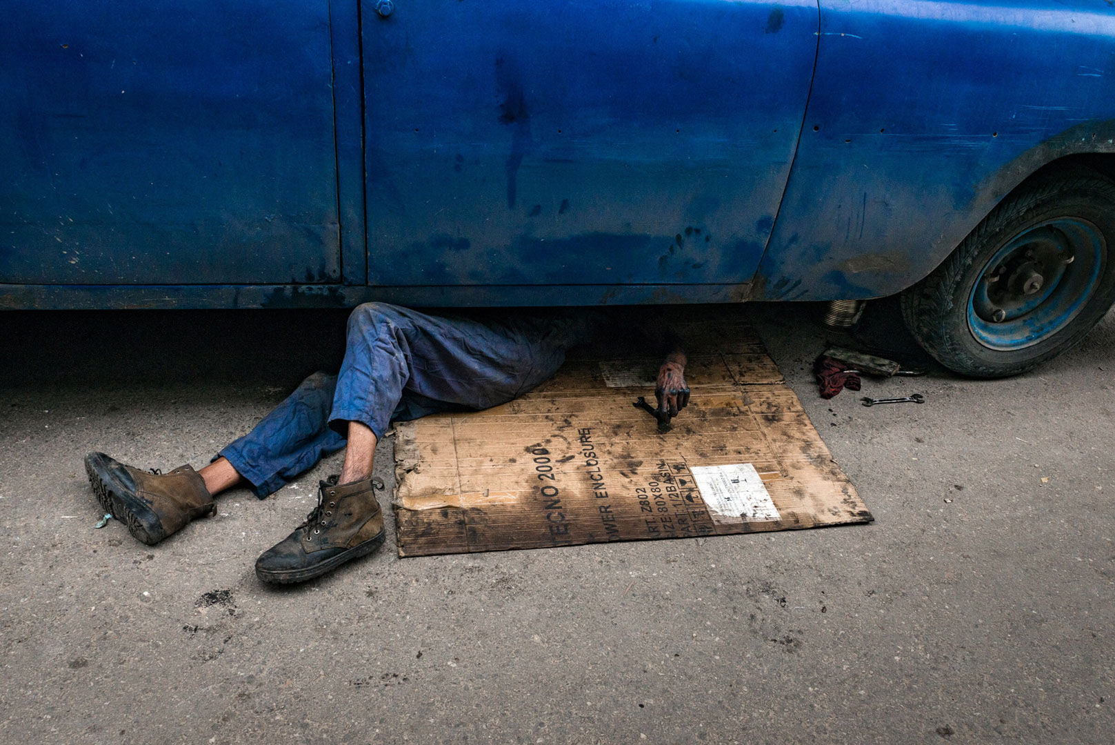 The Mechanic: A photograph by guest artist Branden Eastwood showing a mechanic working on a car in Havana.
