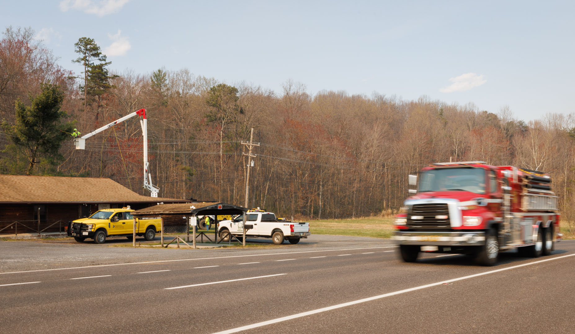 A fire truck rushes west on Rt. 211 Wednesday afternoon, passing a Rappahannock Electric Cooperative (REC) work crew fixing power lines at the old gun shop in Washington, Va.