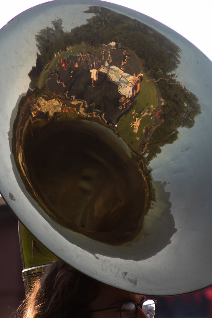 A reflection of the wind players warming up ahead of rehearsal in sousaphonist Declan Perrot's instrument bell. (Photo/Ireland Hayes for Foothills Forum)