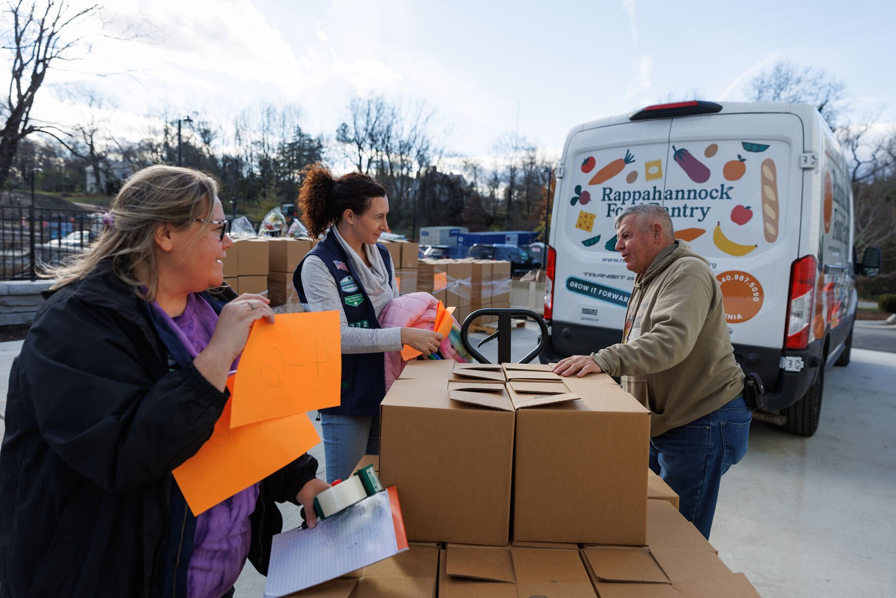 Volunteers Sharon Ennis and Erin Knuckles with Rappahannock Food Pantry Vice President of Operations Pete Stenner tally up the over 250 boxes of dry goods and produce for Thanksgiving.