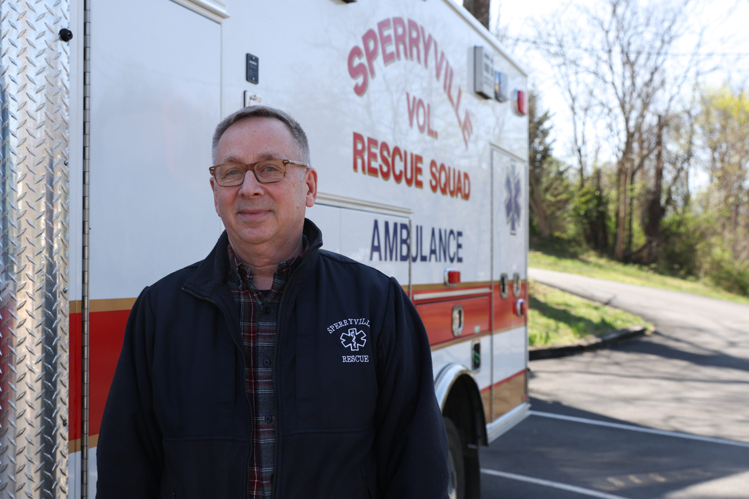 Todd Summers smiling, standing next to a Sperryville Rescue Squad ambulance with the logo showing in the backgound.